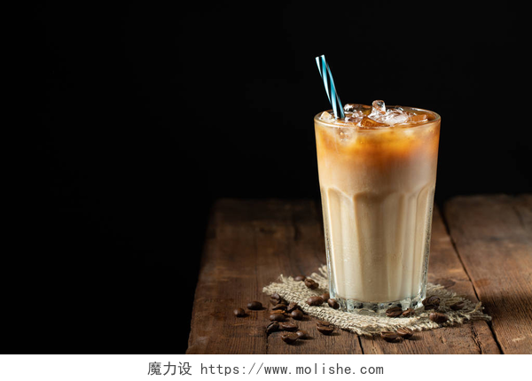 木制的桌子上一杯咖啡冰咖啡在一个高大的玻璃与奶油倒在和咖啡豆在一个古老的质朴的木桌上。冰冷的夏日饮料, 在黑色的木质背景上复制空间